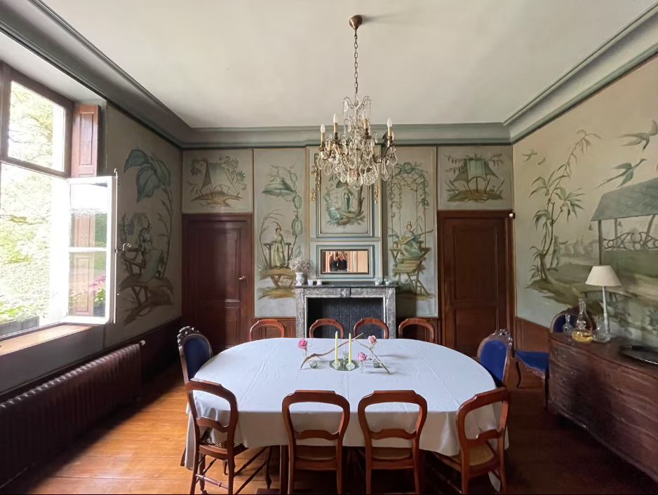 Dining room with hand-painted chinoiserie murals, a crystal chandelier and a long table set for a shared meal